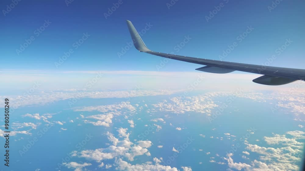Airplane wing flying high above the clouds in a clear blue sky in 4k Airplane wing flying high above the clouds in a clear blue sky in 4k