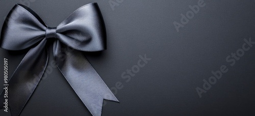 Black ribbon bow on a black background, top view. Banner for product presentation in a business or holiday concept.