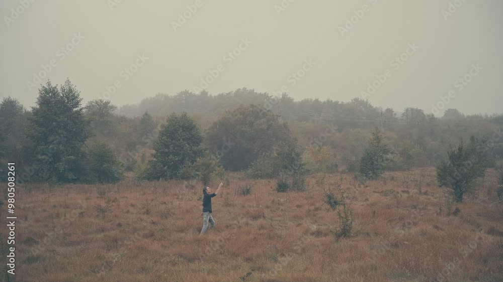 Young man of European appearance in a black shirt with long black hair in nature, fog, morning, autumn, running in the field, looking at phone, trying to catch a signal, long shot, close-up, lost Young man of European appearance in a black shirt with long black hair in nature, fog, morning, autumn, running in the field, looking at phone, trying to catch a signal, long shot, close-up, lost