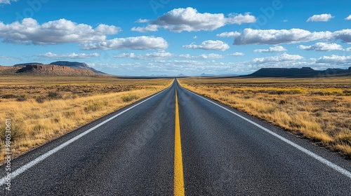 A serene landscape featuring a straight road stretching through open plains under a vibrant blue sky with scattered clouds. photo