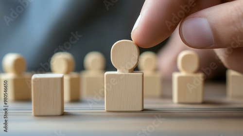 Hand Selecting a Wooden Human Figure from a Set of Blocks for Employment or Team Building Concept