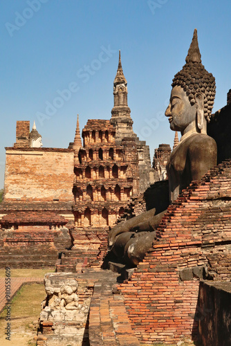 Big sitting buddha statue at the Wat Mahathat Temple with many chedis, stupas, towers in the background, Historical Park, archaeological site, ancient ruins of Sukhothai, Thailand photo