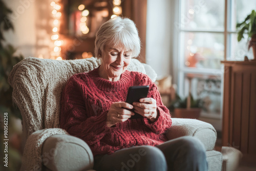 Elderly lady embraces modern technology, focusing on mobile device while relaxing in comfortable living room, defying age stereotypes photo