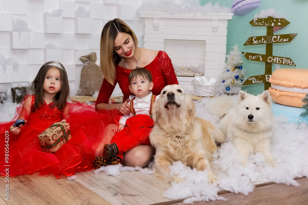 Family photo portrait. Mom and her two children and two white dogs in red clothes celebrate the Chistmas, new year. Happy young mother and her daughter, son and dogs in a cozy dark living room on Family photo portrait. Mom and her two children and two white dogs in red clothes celebrate the Chistmas, new year. Happy young mother and her daughter, son and dogs in a cozy dark living room on