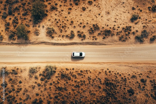 Desert road top view of car driving through the deserted area with dry land along dirt road
