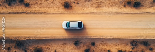 Desert road top view of car driving through the deserted area with dry land along dirt road