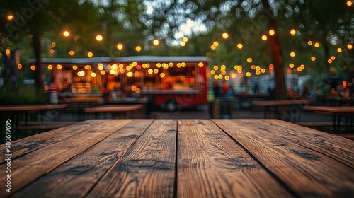 Empty wooden tables on blurred food truck festival and bright decoration lights