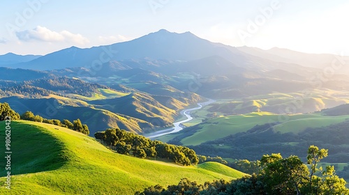 A majestic mountain range bathed in golden sunlight, with rolling green hills and a winding river snaking through the valley. The scene is captured with a deep depth of field, showcasing the vastness photo