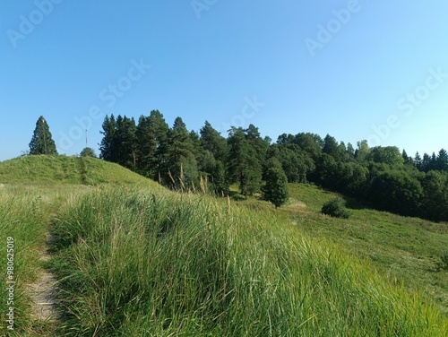 Bubiai hill during sunny day. Small hill. Grass is growing on hill. Staircase leading to the top. Sunny day with white and gray clouds in sky. Nature. Bubiu piliakalnis. 