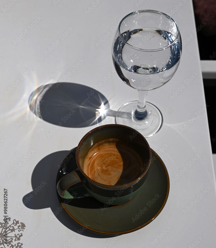 Cup of espresso and glass of water on the table in cafe