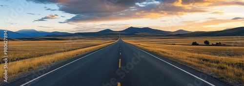 A long road in the middle of nowhere, with beautiful scenery on both sides and mountains visible at sunset. 