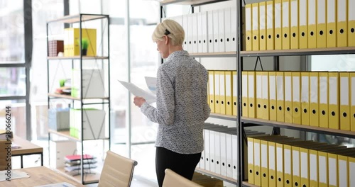 Call center customer service employee holds documents walks around office communicates with business partner. Manager in headphones holding paper and talking to client or customer photo