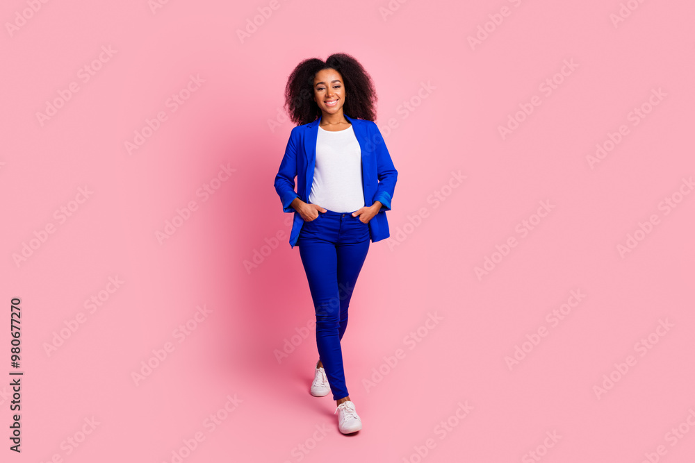 Full size photo of positive girl with wavy hairstyle dressed blue jacket standing hold arms in pockets isolated on pink color background Full size photo of positive girl with wavy hairstyle dressed blue jacket standing hold arms in pockets isolated on pink color background