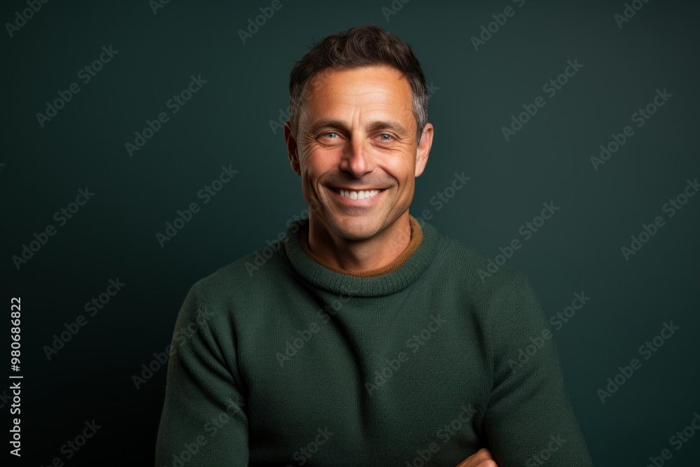 Portrait of a smiling man in his 40s dressed in a warm wool sweater isolated in pastel teal background Portrait of a smiling man in his 40s dressed in a warm wool sweater isolated in pastel teal background