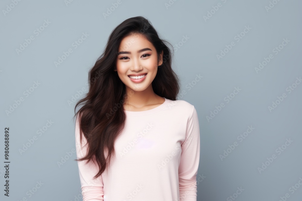 Portrait of a cheerful asian woman in her 20s sporting a long-sleeved thermal undershirt over pastel gray background Portrait of a cheerful asian woman in her 20s sporting a long-sleeved thermal undershirt over pastel gray background