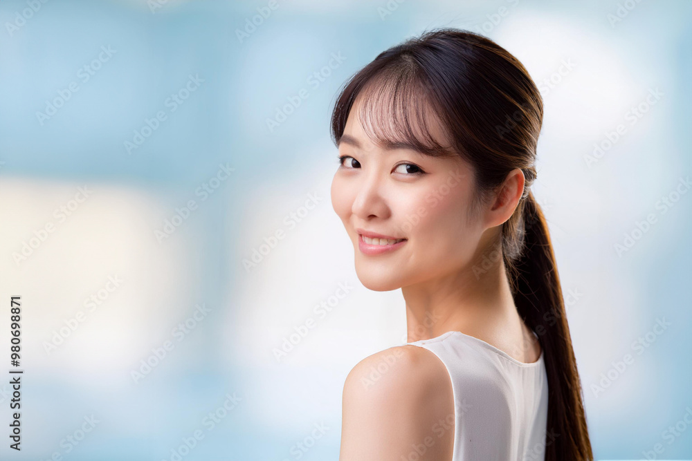 A young, attractive and beautiful Asian woman with long dark hair, smiling softly over her shoulder against a softly blurred background. Copy space available for design. A young, attractive and beautiful Asian woman with long dark hair, smiling softly over her shoulder against a softly blurred background. Copy space available for design.
