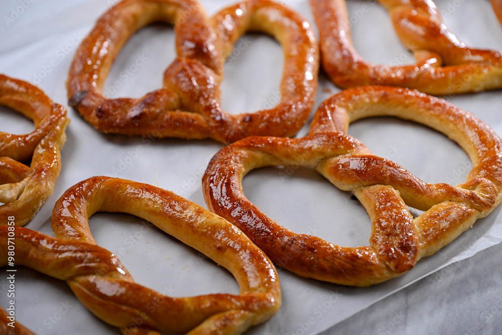 Freshly baked, golden-brown pretzels laid out on parchment paper, glistening with a slight sheen of butter. These crispy yet soft pretzels are perfect for snacking Freshly baked, golden-brown pretzels laid out on parchment paper, glistening with a slight sheen of butter. These crispy yet soft pretzels are perfect for snacking