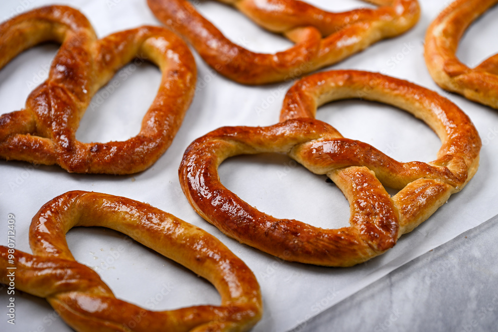 Freshly baked, golden-brown pretzels laid out on parchment paper, glistening with a slight sheen of butter. These crispy yet soft pretzels are perfect for snacking Freshly baked, golden-brown pretzels laid out on parchment paper, glistening with a slight sheen of butter. These crispy yet soft pretzels are perfect for snacking