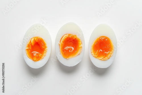 Three perfectly boiled eggs sit in a row, their creamy whites encasing rich, golden yolks. The simplicity of the arrangement highlights the textures and colors, inviting a sense of calm and purity.