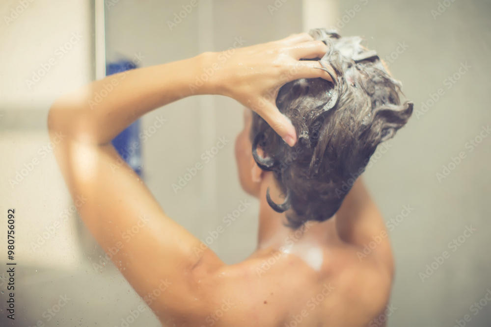 Naklejka premium Woman in shower rinse shampoo foaming with water dripping on hair and body. Taking shower relaxing under warm running water. Female washing her hair and hand to massage head while washing hair.