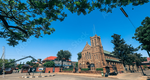 Historic stone church in Bulawayo surrounded by greenery and clear skies during the day photo