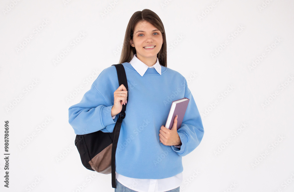Caucasian girl student in blue sweatshirt with folder, books, notebook, notepad in hands smiling isolated on white studio background, copy space