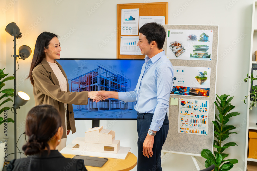 Asian Architects and department manager teamwork shaking hands after success presentation 3D architectural displayed model of energy efficient and sustainability home design in office conference room Asian Architects and department manager teamwork shaking hands after success presentation 3D architectural displayed model of energy efficient and sustainability home design in office conference room