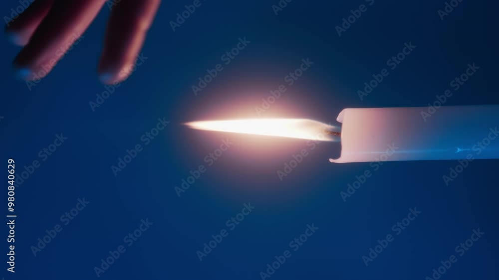 Detail shot of womans hand playing with flame of white candle placed in horizontal position on blue background Detail shot of womans hand playing with flame of white candle placed in horizontal position on blue background