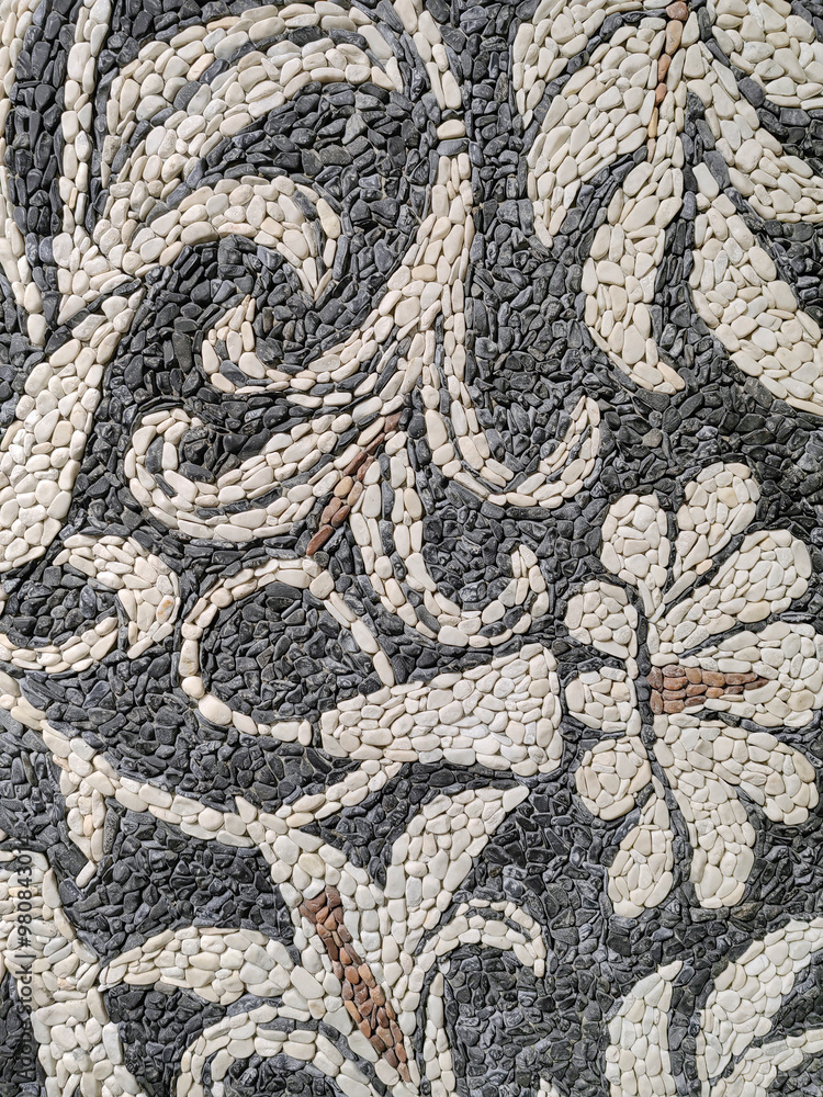 Floor pavement made of round small stones in white and black form flowers as decoration. Floor pavement made of round small stones in white and black form flowers as decoration.