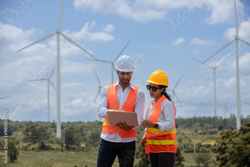 Team engineer wearing safety uniform holding laptop discussed plan about renewable energy at station energy power wind. technology protect environment reduce global warming problems.