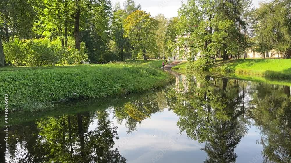 Video of beautiful summer landscape with reflection in river of green trees on Catherine park of Tsarskoe Selo on sunny day. Pushkin, Saint Petrsburg, September 2024 Video of beautiful summer landscape with reflection in river of green trees on Catherine park of Tsarskoe Selo on sunny day. Pushkin, Saint Petrsburg, September 2024