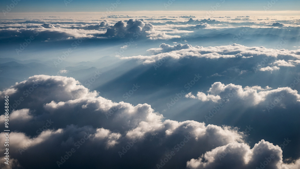 Sun rays shining through clouds in a vivid blue sky during a serene and breathtaking aerial view above clouds. Sun rays shining through clouds in a vivid blue sky during a serene and breathtaking aerial view above clouds.