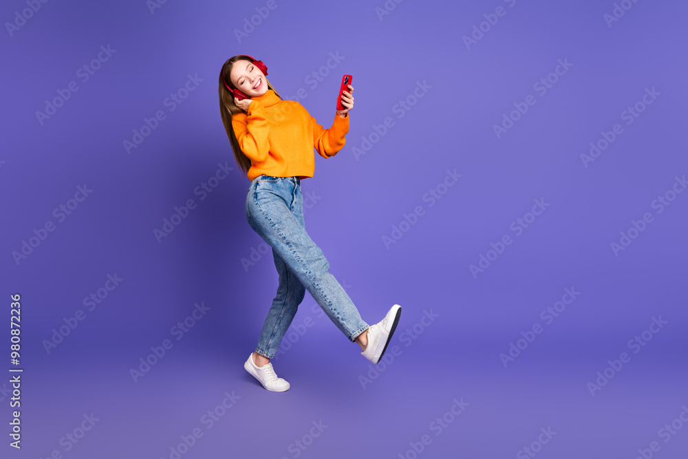 Photo of blonde hair cheerful youngster girl using her smartphone meloman wearing earphones isolated on purple color background Photo of blonde hair cheerful youngster girl using her smartphone meloman wearing earphones isolated on purple color background