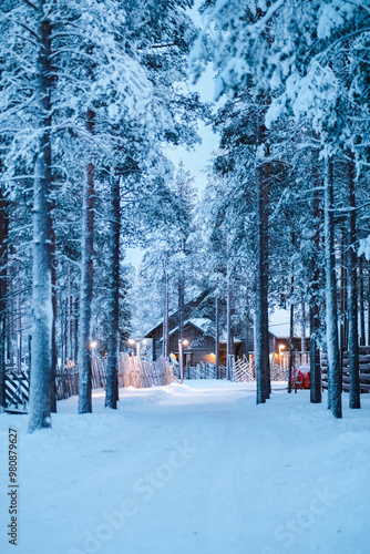 Wooden Cabin House with Bright Lights At the End of a Snow Covered Street in the Forest