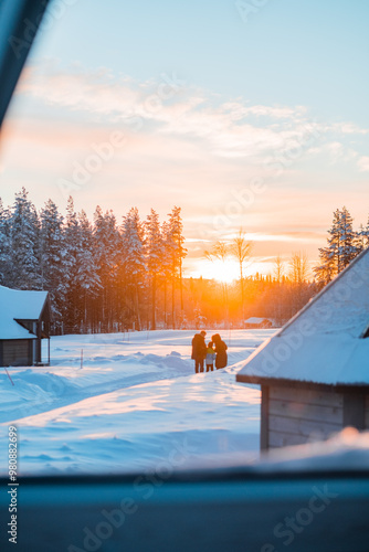 Two Parents and One Child Looking Against the Sunrise Morning Sunlight in a Snow Landscape
