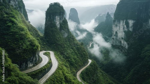 The winding Tianmen Mountain road snaking through lush green cliffs, with mist rising from the valley below. photo