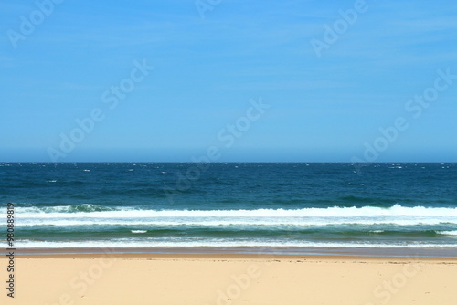 Crowded Sandy Beach With People Enjoying The Waves Of The Blue Ocean On A Summer Day