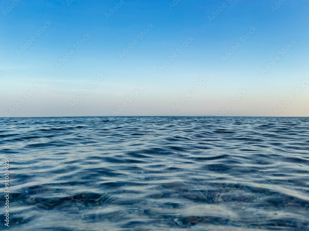 Calm sea under a blue sky at sunrise. calm colors. waterline. waves. ripples. sea water surface. Calm sea under a blue sky at sunrise. calm colors. waterline. waves. ripples. sea water surface.