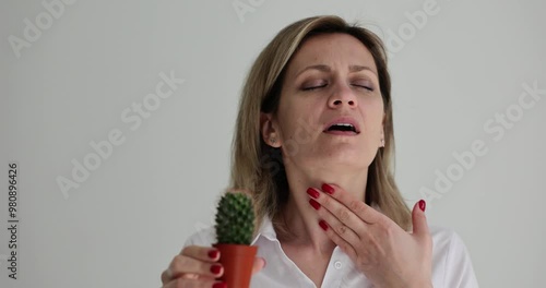 Portrait of sick girl with problems in throat with cactus. Woman holding her neck and sore throat