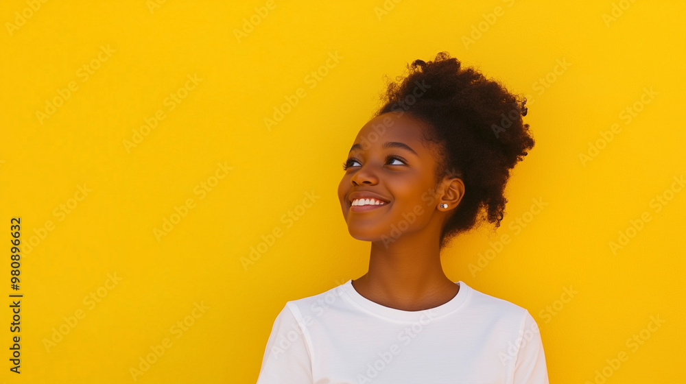 Happy and confident African American Gen Z teen girl standing against a bright yellow wall, wearing a joyful smile. She gazes off into the distance, daydreaming, and radiating posi Happy and confident African American Gen Z teen girl standing against a bright yellow wall, wearing a joyful smile. She gazes off into the distance, daydreaming, and radiating posi
