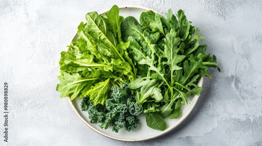 A selection of leafy greens like spinach, kale, and arugula on a white plate, leaving space for text on the right side. A selection of leafy greens like spinach, kale, and arugula on a white plate, leaving space for text on the right side.