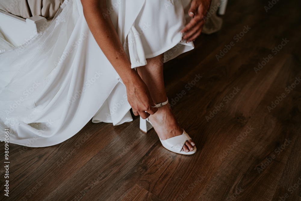 Mujer con vestido blanco de novia se calza zapatos blancos Mujer con vestido blanco de novia se calza zapatos blancos