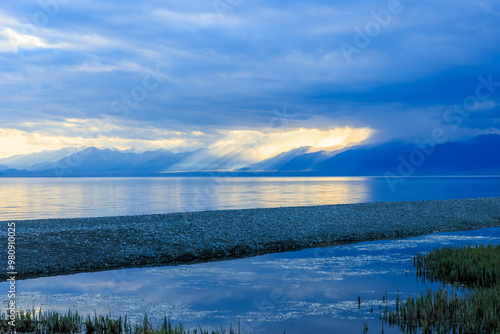 Gravel road beside the lake. Road and lake with mountain nature landscape at sunset.