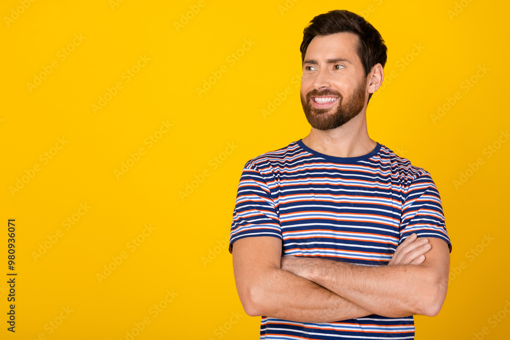 Portrait of handsome confident businessman in striped t shirt crossed hands looking empty space minded isolated on yellow color background Portrait of handsome confident businessman in striped t shirt crossed hands looking empty space minded isolated on yellow color background