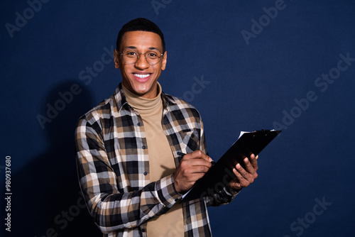 Photo of cheerful positive guy dressed plaid shirt signing contract emtpy space isolated blue color background