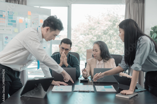 Group of Asian business people in conference room for business presentation or seminar. Documents have financial or marketing figures, graphs and charts. There is a laptop to analyze company stocks.