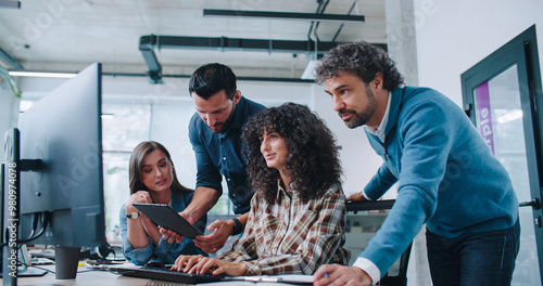 Group of smart Caucasian coworkers intently looking at computer screen. People brainstorming about working plan or searching for solution to issue. Men and women positively communicating.