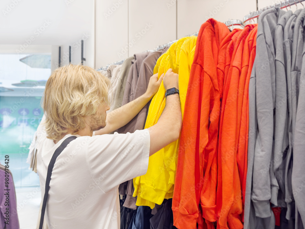 young man choosing clothes in a shopping mall. clothes hangers
