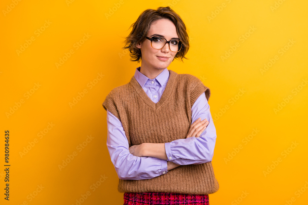 Portrait of good mood woman with bob hairstyle wear knit waistcoat in glasses holding hands crossed isolated on yellow color background Portrait of good mood woman with bob hairstyle wear knit waistcoat in glasses holding hands crossed isolated on yellow color background