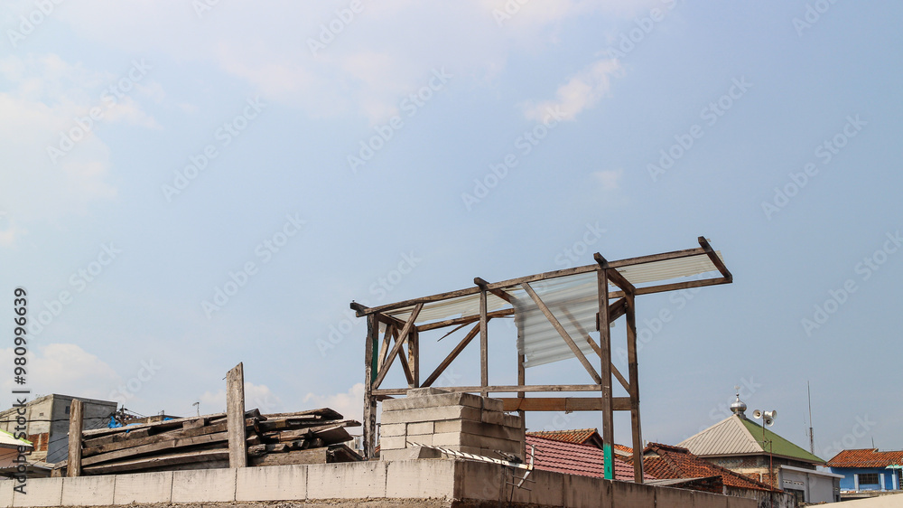 A wooden frame on a rooftop with a clear sky above. A wooden frame with a clear plastic roof sits on a rooftop. A wooden frame on a rooftop with a clear sky above. A wooden frame with a clear plastic roof sits on a rooftop.